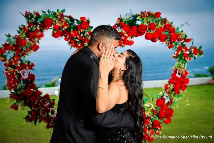 Bianca and Violan share a kiss in front of the rose heart arch, the ocean behind them